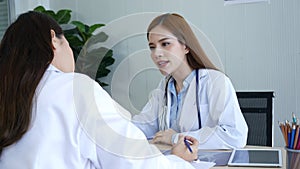 Two women doctors consultation with professional specialist diagnostics at hospital medicare treatment clinic. Doctor writing pres