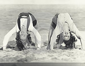 Two women doing backbends on the beach