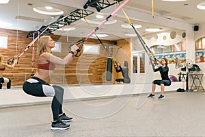 Two women doing group workout with fitness straps in gym. Sport, fitness, training, healthy lifestyle concept