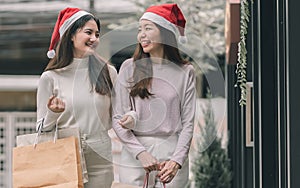 Two women doing window shopping and holding bags in christmas season