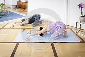 Two women doing yoga at home Balasana variation photo