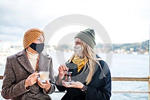 two women drinking turkish tea and salep while wearing medical mask coronavirus time