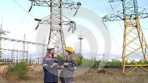 Two women energy workers conducts an inspection of equipment and power lines