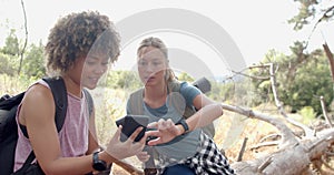 Two women are examining a smartphone during a hike in the woods