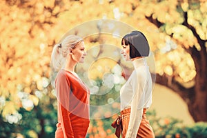 Two women are facing each other. girls looking into each others eyes. female friendship. walking in sunny park. best