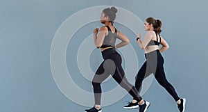 Two women in fitness wear jogging outdoors at a wall