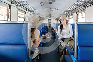 Two women friend talk and laugh while travel by train, railroad trip concept