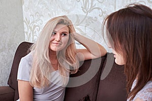 Two women friends chatting on the couch at home