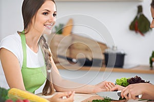 Two women friends cooking in kitchen while having a pleasure talk. Friendship and Chef Cook concept