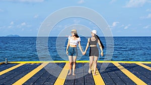 Two women friends or couples relaxing in the sea and walking at tropical beach travel summer holidays. Female tourists enjoy