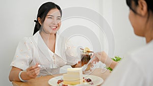 Two women friends enjoy eating dessert and chatting in the cafe together