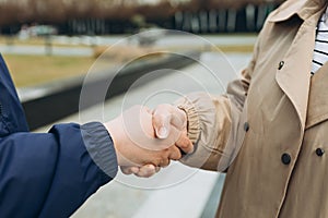 Two women friends or female partners meet on street. Handshake of two Successful business women on the background of