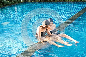 Two women friends having fun together in pool