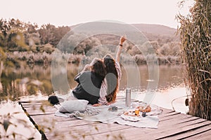 Two women friends having picnic in autumn forest near lake.