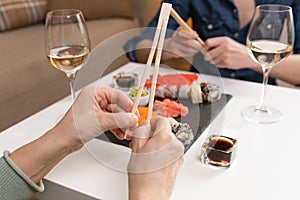 Two women friends sitting by table and eating sushi. Family, friendship and communication concept