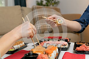 Two women friends sitting by table and eating sushi. Family, friendship and communication concept