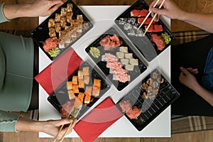 Two women friends sitting by table and eating sushi. Family, friendship and communication concept