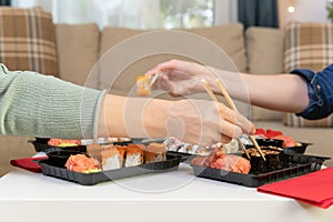 Two women friends sitting by table and eating sushi. Family, friendship and communication concept