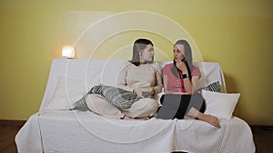 Two women girlfriend watching television together on the couch at home