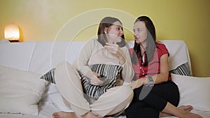 Two women girlfriend watching television together on the couch at home