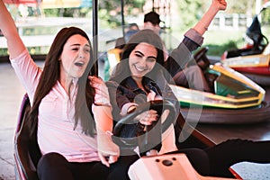 Two women having a lot of fun in the amusement park, driving bumper cars