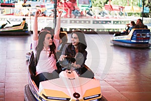 Two women having a lot of fun in the amusement park, driving bumper cars