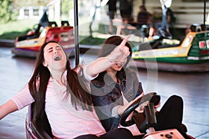 Two women having a lot of fun in the amusement park, driving bumper cars