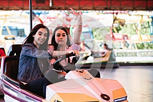 Two women having a lot of fun in the amusement park, driving bumper cars