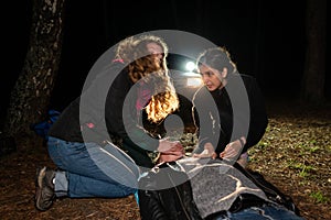 Two women are helping a man lying on the ground. One of the women looks around