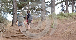 Two women hike on a rugged trail amidst trees and dry grass with copy space