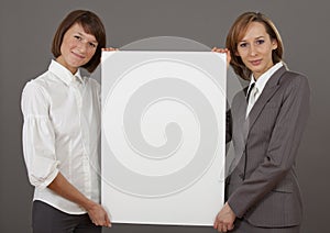 Two women holding blank board