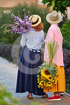 two women holding a bouquet of sunflowers and gladiolus flowers, summer concept