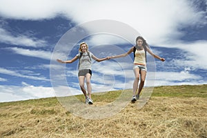 Two Women Holding Hands And Skipping Down Hill