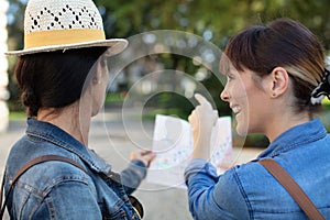 Two women holding map in hand together while pointing direction