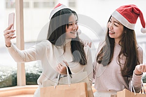 Two women holding shopping bags and selfie in christmas season