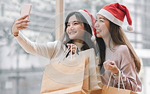 Two women holding shopping bags and selfie in christmas season