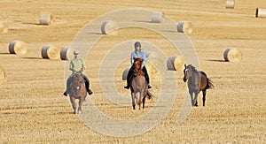 Two Women Horseback Riding in a Field