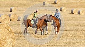 Two Women Horseback Riding in a Field