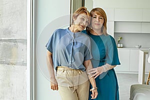 Two women hugging, indoor portrait