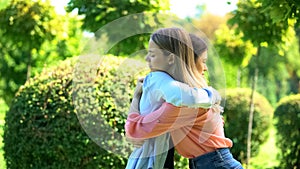 Two women hugging outdoor saying good-bye, friendship trusting relationship