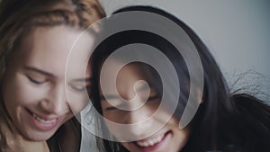 Two women hugging and smiling at each other in bedroom. Portrait of lesbian couple spend time together at home. LGBTQI