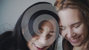 Two women hugging and smiling at each other in bedroom. Portrait of lesbian couple spend time together at home. LGBTQI