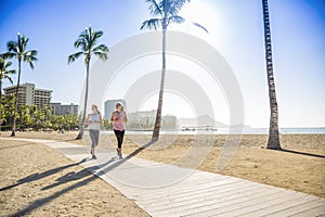 Two Women jogging on the beach boardwalk between two palm trees