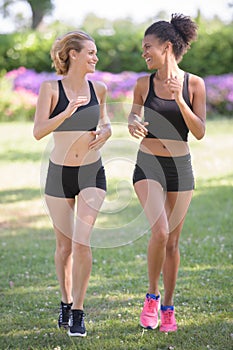 two women jogging in park and listening to music