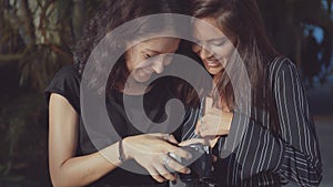 Two women laughingly examine pictures taken on camera