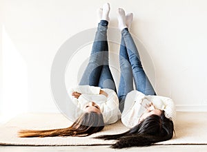 Two women laying at the rug legs up having fun