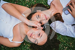 Two women listening to music laying down on grass