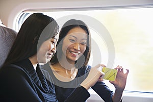 Two Women Looking At Mobile Phone on a Train