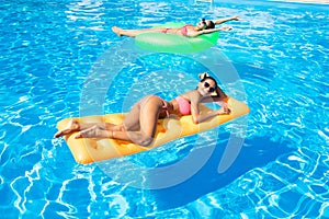 Two women lying on air mattress in the swimming pool