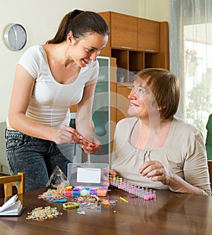 Two women make bracelets at home